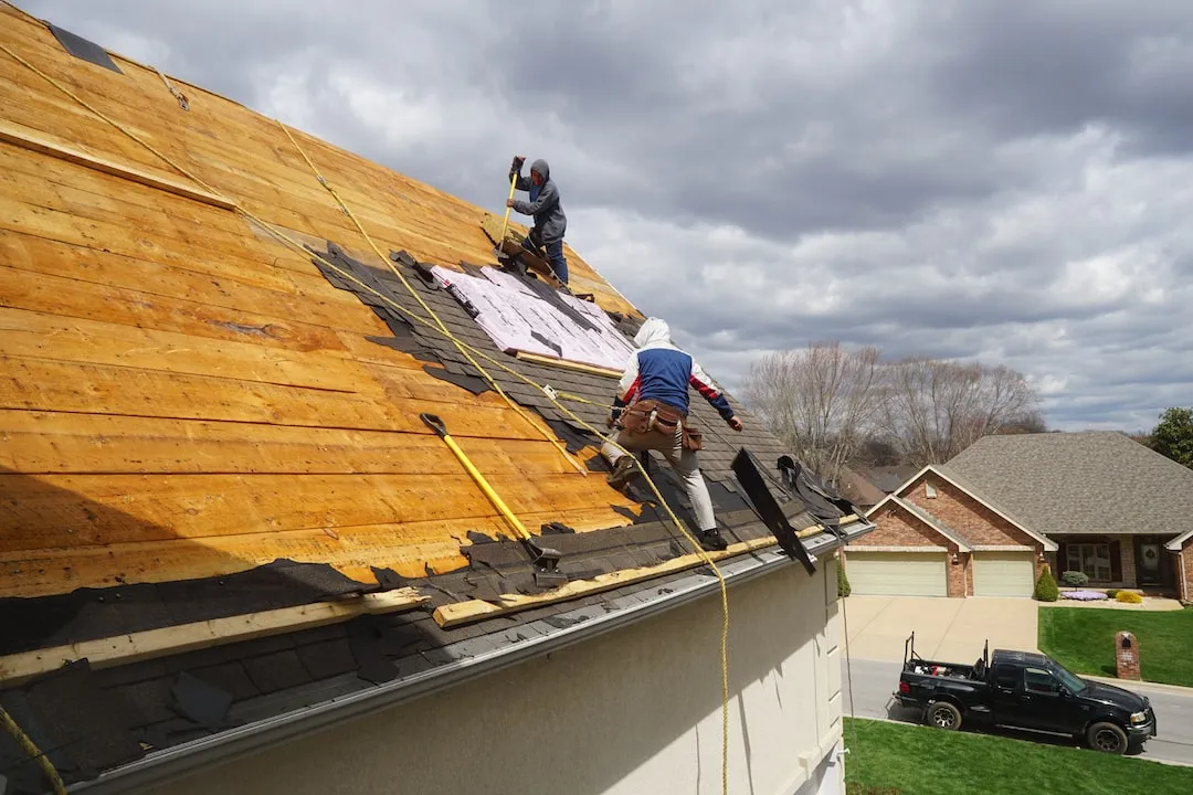 Residential roof with storm damage being repaired by a professional roofing crew